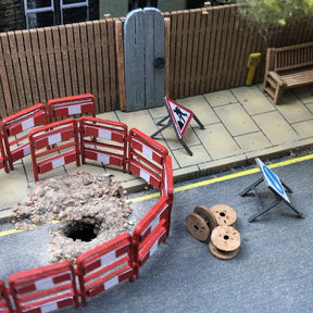 A OO gauge/OO scale roadworks scene with temporary traffic signs and folding road barriers.